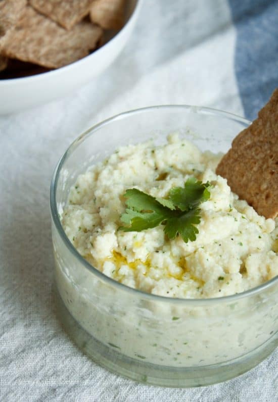 Heart of Palm dip in glass bowl with leaf garnish and cracker dipped in